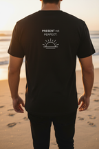 Back of black PRESENT not PERFECT tee – sunset beach walk