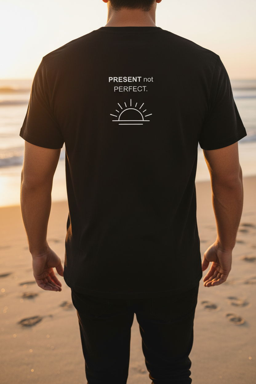 Back of black PRESENT not PERFECT tee – sunset beach walk